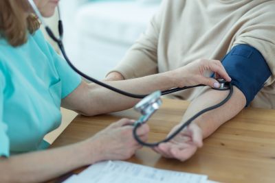 Medicinska sestra meri krvni tlak starejši osebi na domu
