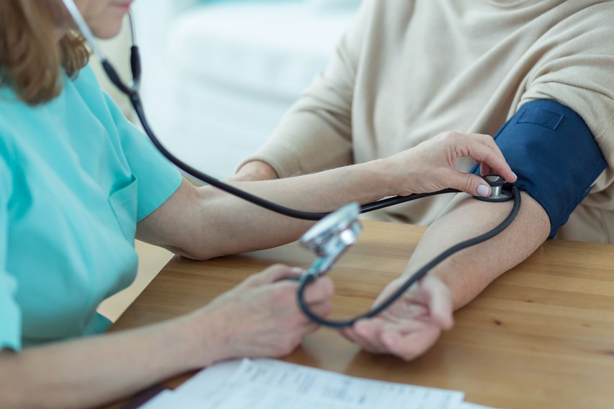 Medicinska sestra meri krvni tlak starejši uporabnici na domu