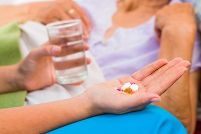 Medicinska sestra pripravi zdravila in kozarec vode za uporabnico
