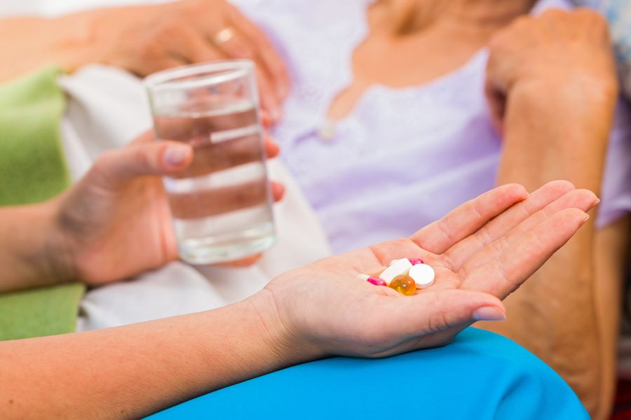 Medicinska sestra pripravi zdravila in kozarec vode za uporabnico